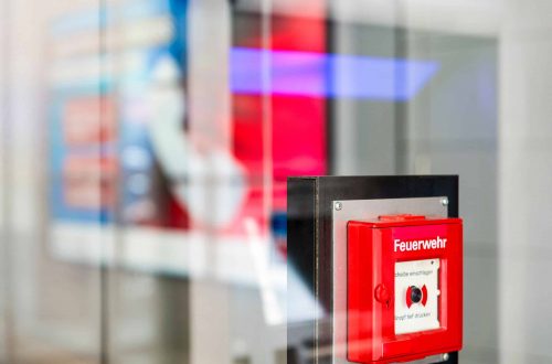 Alarmknopf für die Feuerwehr hinter einer Glasscheibe.
